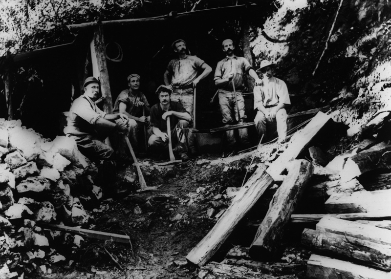 A group of miners standing outside the entrance of a goldmine gallery